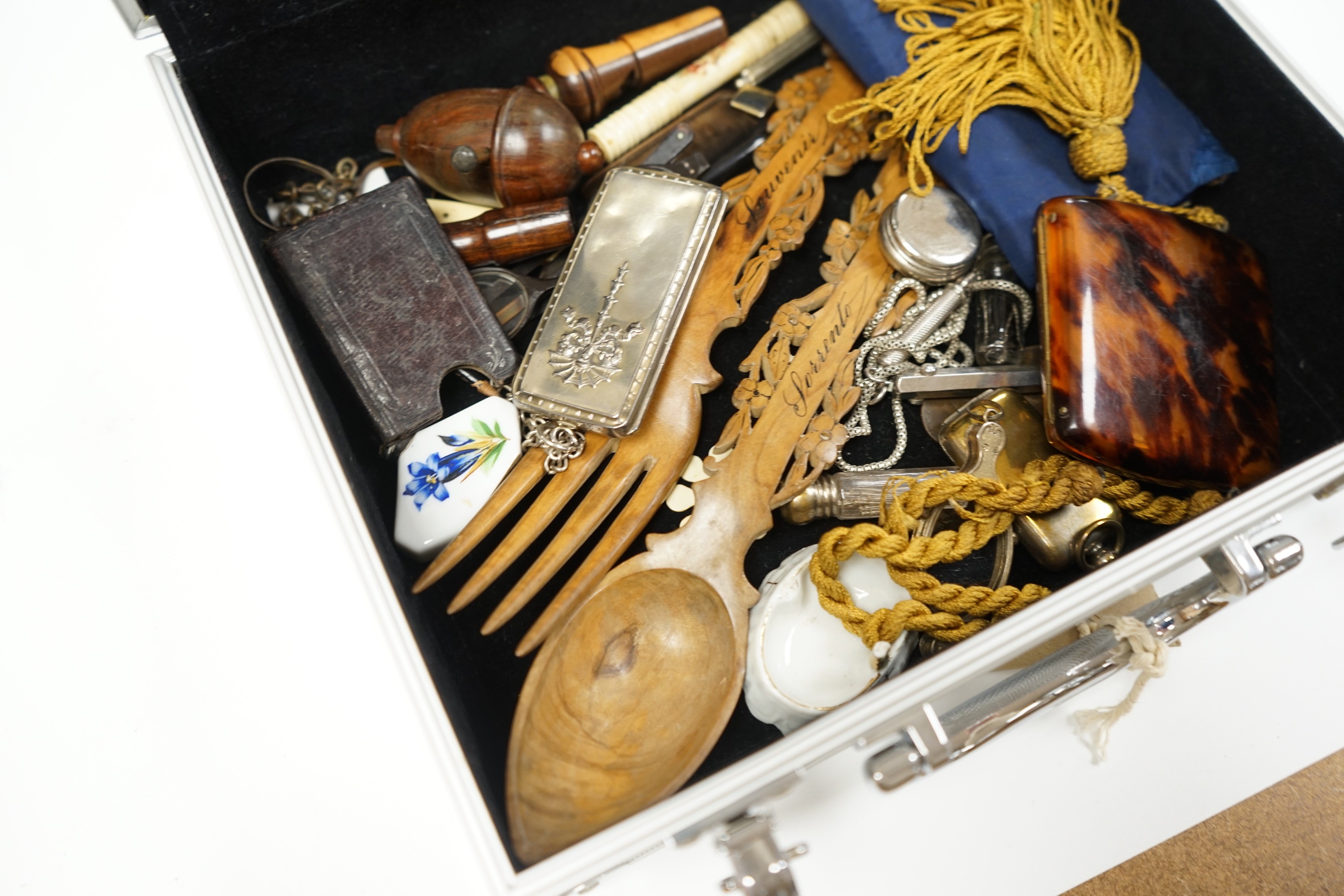 A metal case containing mixed collectibles including treen whistles, a cigarette case, three white metal propelling pencils etc